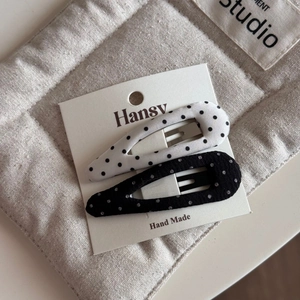 Close-up of black and white polka dot fabric bow hair clips on a white display card