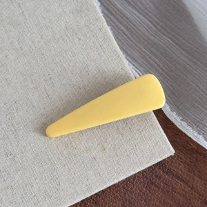 Gros plan sur la pince à cheveux jaune fromage minimaliste sur un tissu texturé