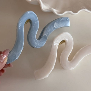 Detailed macro view of wavy marble texture hair claw clips with strong gold metal springs