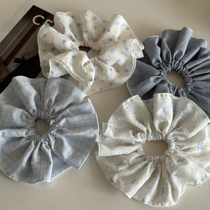 Close-up of four oversized scrunchies in blue and white patterns like dots and checks