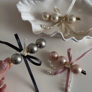 Detail view of pearl bow hair clips in cream, grey and pink colors with silk fringe