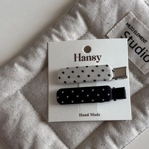 Close-up of black and white polka dot hair clips on a soft quilted fabric background