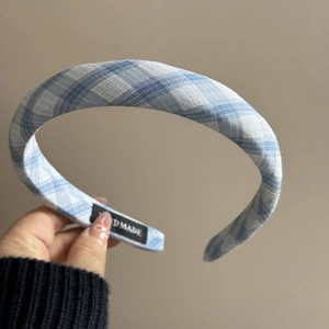 Détail du serre-tête à carreaux bleus montrant la texture et l'étiquette faite main