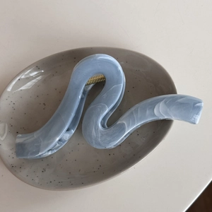 Detail of light blue marble wave hair claw clip featuring golden metal spring mechanism