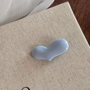 Detail of light blue heart-shaped resin accessory with a glossy polished ceramic-like finish