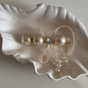 Close-up of elegant bow hair clip with cream pearls, heart rhinestone and silk tassels