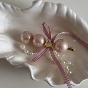 Detail of pink ribbon bow hair clip with pearls, heart zircon, and dangling tassels