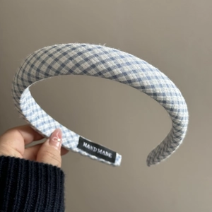 Détail d'un serre-tête rembourré à carreaux bleus avec étiquette faite à la main