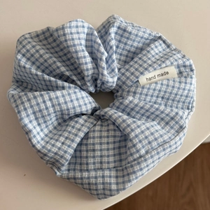Gros plan sur un chouchou à carreaux bleus avec étiquette faite main sur tissu