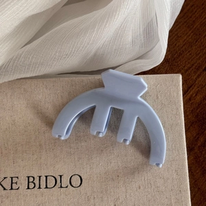 Close-up of a matte light blue hair claw clip on an elegant minimalist background