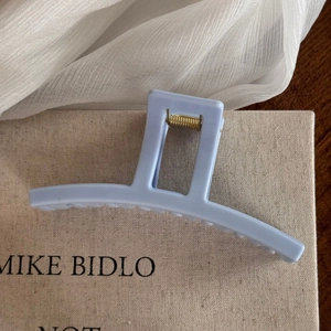 Close-up of matte light blue hair claw clip with golden spring and anti-slip teeth