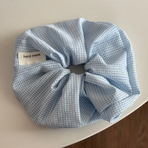 Détail macro du chouchou à carreaux bleu clair avec étiquette tissée fait main