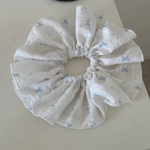 Detailed close-up of a white oversized scrunchie with light blue bow and polka dot patterns