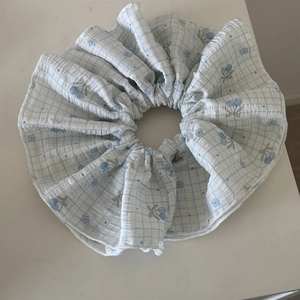 Detail of blue plaid scrunchie with floral cherry patterns on seersucker fabric