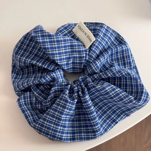 Détail d'un chouchou bleu à carreaux avec motif classique et étiquette de qualité