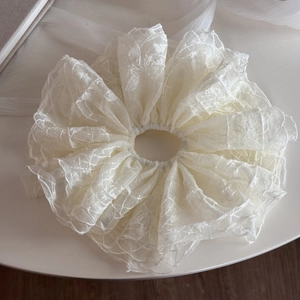 Détail du chouchou en dentelle blanche avec broderie florale et tissu mesh étagé
