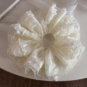 Vue détaillée du chouchou géant en dentelle crème montrant les textures plissées