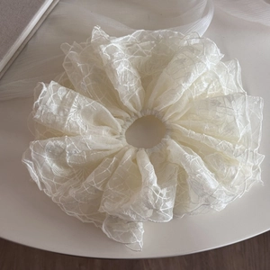 Vue détaillée du chouchou en dentelle crème avec texture florale et maille délicate