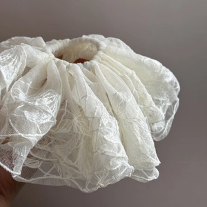 Détail d'un chouchou en dentelle crème avec motifs de broderie florale sophistiqués