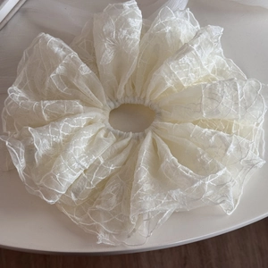 Gros plan d'un chouchou en dentelle blanc crème avec texture en maille fleurie complexe