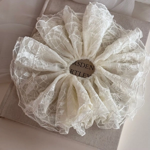 Vue détaillée d'un chouchou en dentelle blanc crème avec motifs floraux ajourés