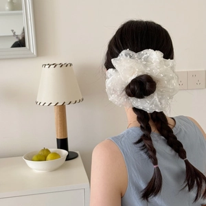 Detailed view of white mesh polka dot scrunchie on a model with low bun hair styling