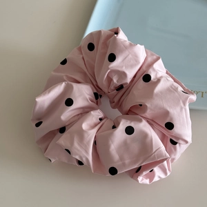 Gros plan d'un chouchou rose à pois noirs posé sur une table au style minimaliste