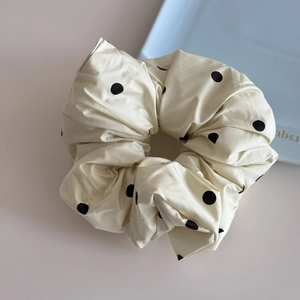 Détail du chouchou en tissu crème doux avec de grands motifs à pois noirs élégants