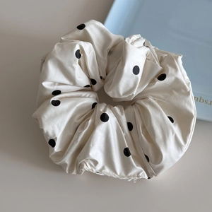 Détail d'un chouchou blanc à pois avec texture soyeuse et plis élégants pour la coiffure