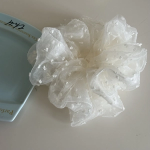 Detailed close-up of white bubble mesh hair scrunchie with embroidered polka dots