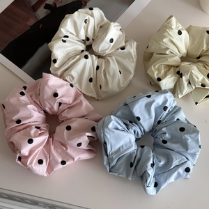Gros plan de quatre chouchous oversize en satin à pois en rose pastel et bleu clair