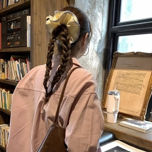 Chouchou en tissu à rayures bleu et jaune sur une coiffure à double tresse
