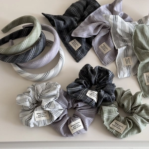 Close-up of striped cotton scrunchie and headband with stitched fabric quote label