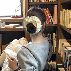 Chouchou géant en tissu rayé jaune et blanc avec bordure bleue sur un chignon