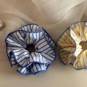 Détail des chouchous rayés bleus et jaunes sur un fond en tissu beige doux et plissé