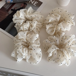 Detailed view of four cream organza scrunchies with black polka dots and pleated texture