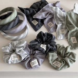 Flat lay of striped fabric hair accessories set in moss green and neutral tones