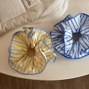 Vue détaillée des chouchous en tissu rayé jaune et bleu avec des bords plissés