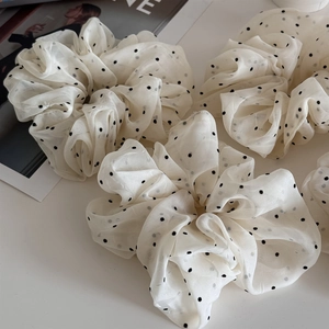 Detail of cream polka dot mesh scrunchie with lightweight ruffled fabric texture