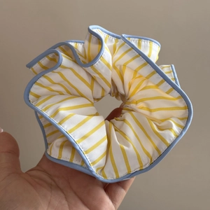 Détail macro d'un grand chouchou rayé jaune et blanc avec bordure de finition bleu clair