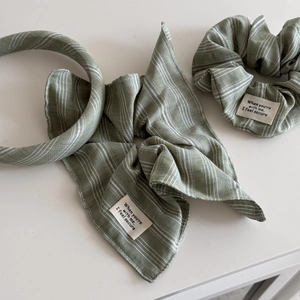 Detailed view of sage green striped hair accessories set including scrunchie and headband