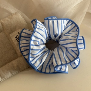 Vue détaillée du grand chouchou en tissu à rayures bleues et blanches avec bords cousus