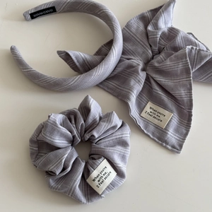 Detail of grey striped hair accessory set featuring scrunchie, headband, and bow with labels