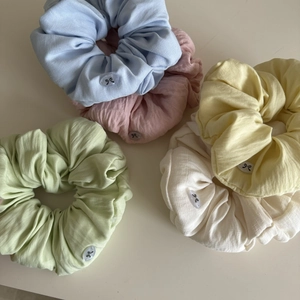 Five-piece set of cream-colored pleated cotton scrunchies with bow button accents
