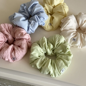Macro view of five macaron-colored cotton hair scrunchies with soft pleated texture