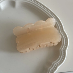 Detail der gewellten Biskuit-Haarklammer in schimmerndem Creme auf einem Keramikteller