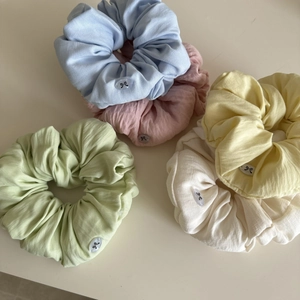Close-up of five macaron-colored hair scrunchies with cute bow button decorations