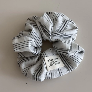Detail of black and white striped scrunchie featuring a white fabric label with text