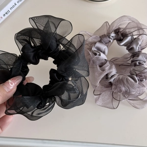 Detail von flauschigen Organza-Haargummis in Schwarz und Lila mit Netzstruktur