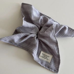 Detailed view of grey striped fabric scrunchie with white woven letter patch tag